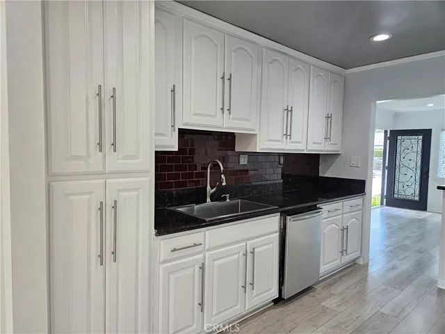 a kitchen with white cabinets and sink