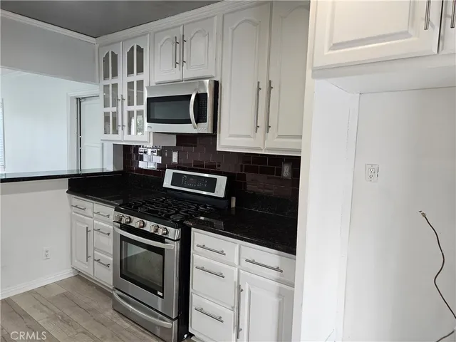 a kitchen with stainless steel appliances granite countertop white cabinets and black stove top oven with granite countertops