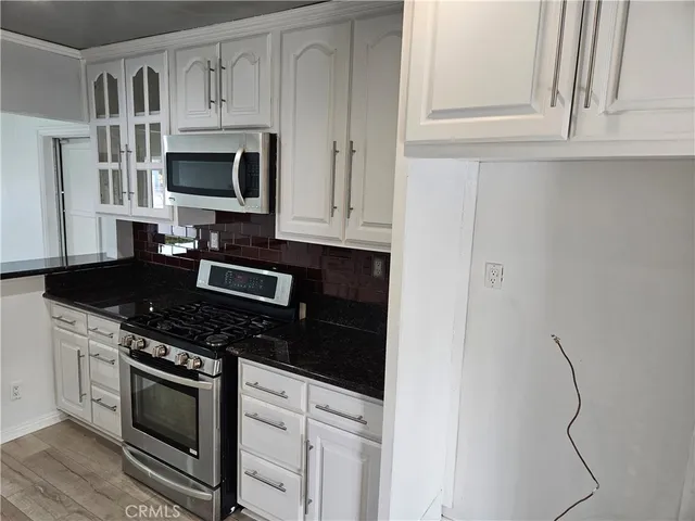 a kitchen with white cabinets and black appliances