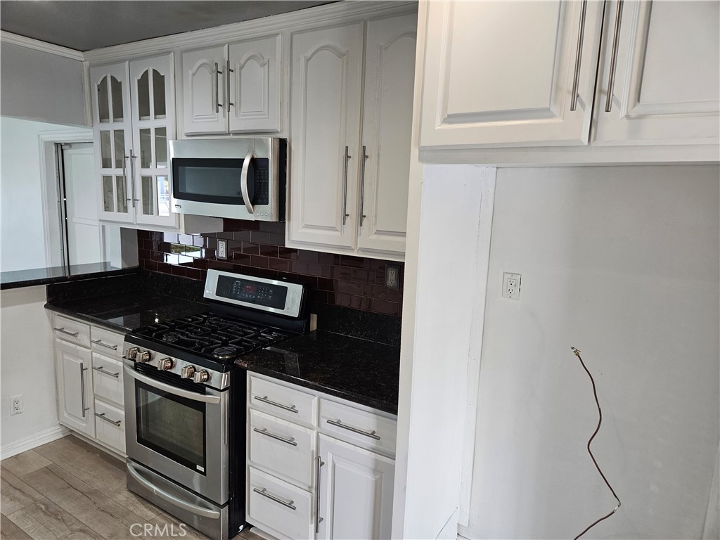 8030 Lemona Avenue Panorama City, CA 91402 - Photo 10 of 29 a kitchen with white cabinets and black appliances