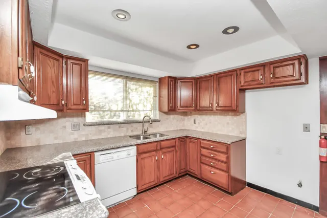 a kitchen with stainless steel appliances granite countertop a sink and cabinets with wooden floor