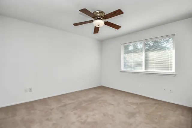 an empty room with ceiling fan and windows