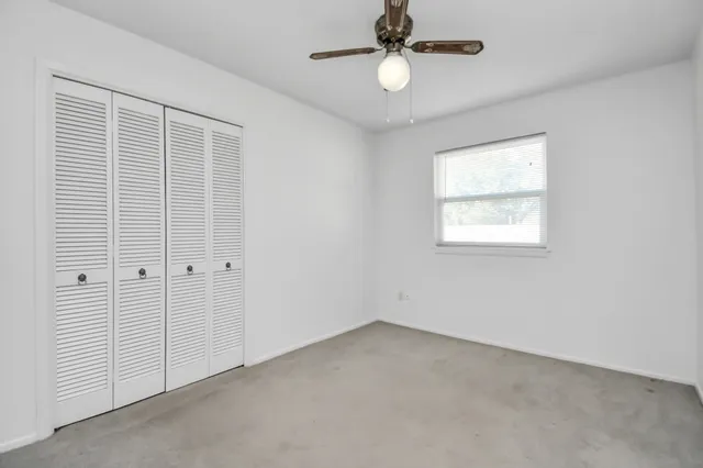 en empty room with windows and ceiling fan