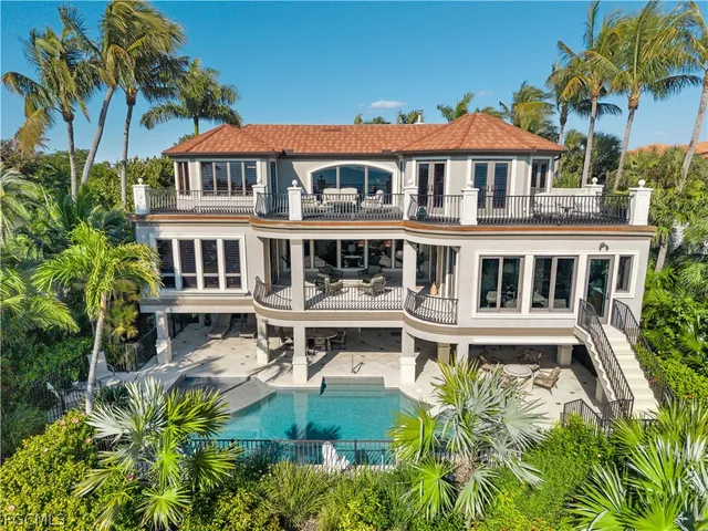a view of a white house with a swimming pool and wooden fence