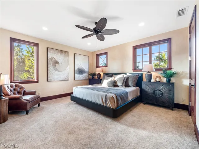 a spacious bedroom with a bed a dresser and a chandelier