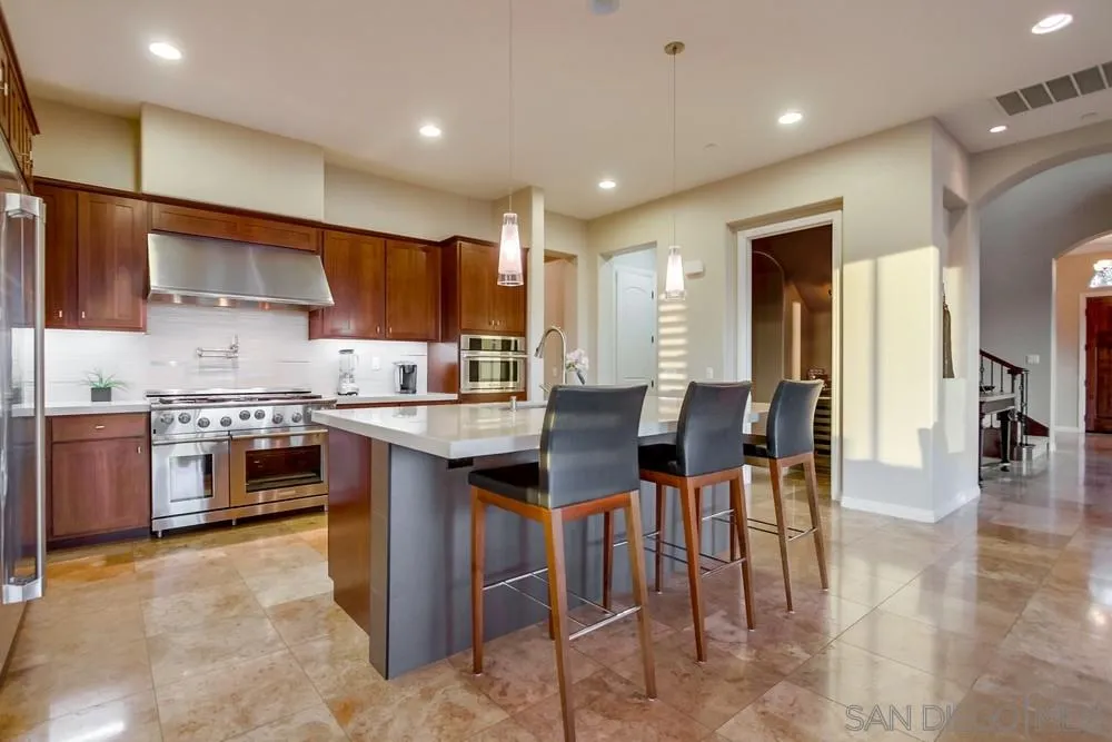 8248 Fortuna Santa Fe Road San Diego, CA 92127 - Photo 18 of 24 a kitchen with stainless steel appliances granite countertop a stove top oven a sink a dining table and chairs