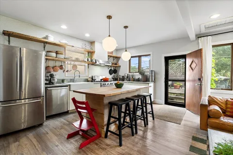 a kitchen with stainless steel appliances kitchen island granite countertop a dining table chairs and white cabinets