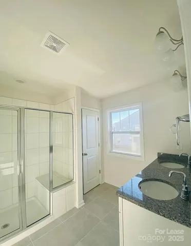 a large bathroom with a glass shower door and a sink