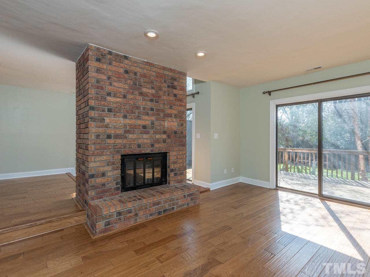 4407 Sunscape Lane Raleigh, NC 27613 - Photo 8 of 29 a living room with a fireplace and wooden floor