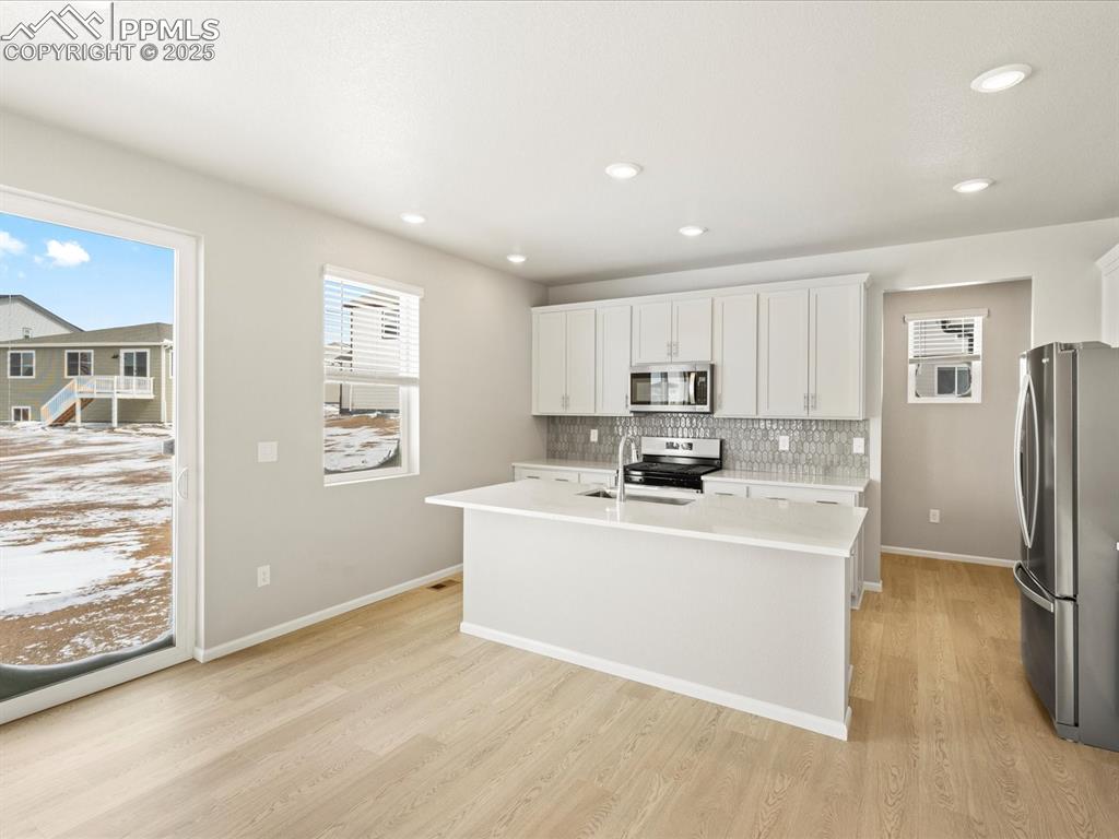 10648 Waterloo Drive Peyton, CO 80831 - Photo 3 of 36 a view of kitchen with stainless steel appliances granite countertop a refrigerator a sink a stove and white cabinets with wooden floor