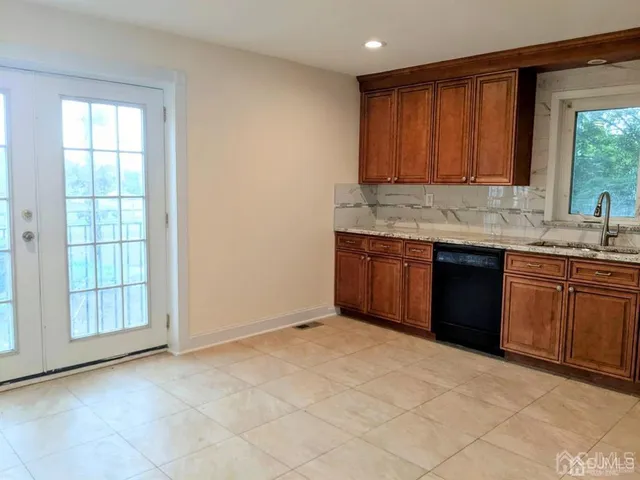 a view of kitchen with granite countertop cabinets sink and dishwasher with wooden floor