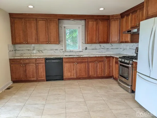 a kitchen with stainless steel appliances granite countertop a sink and a refrigerator