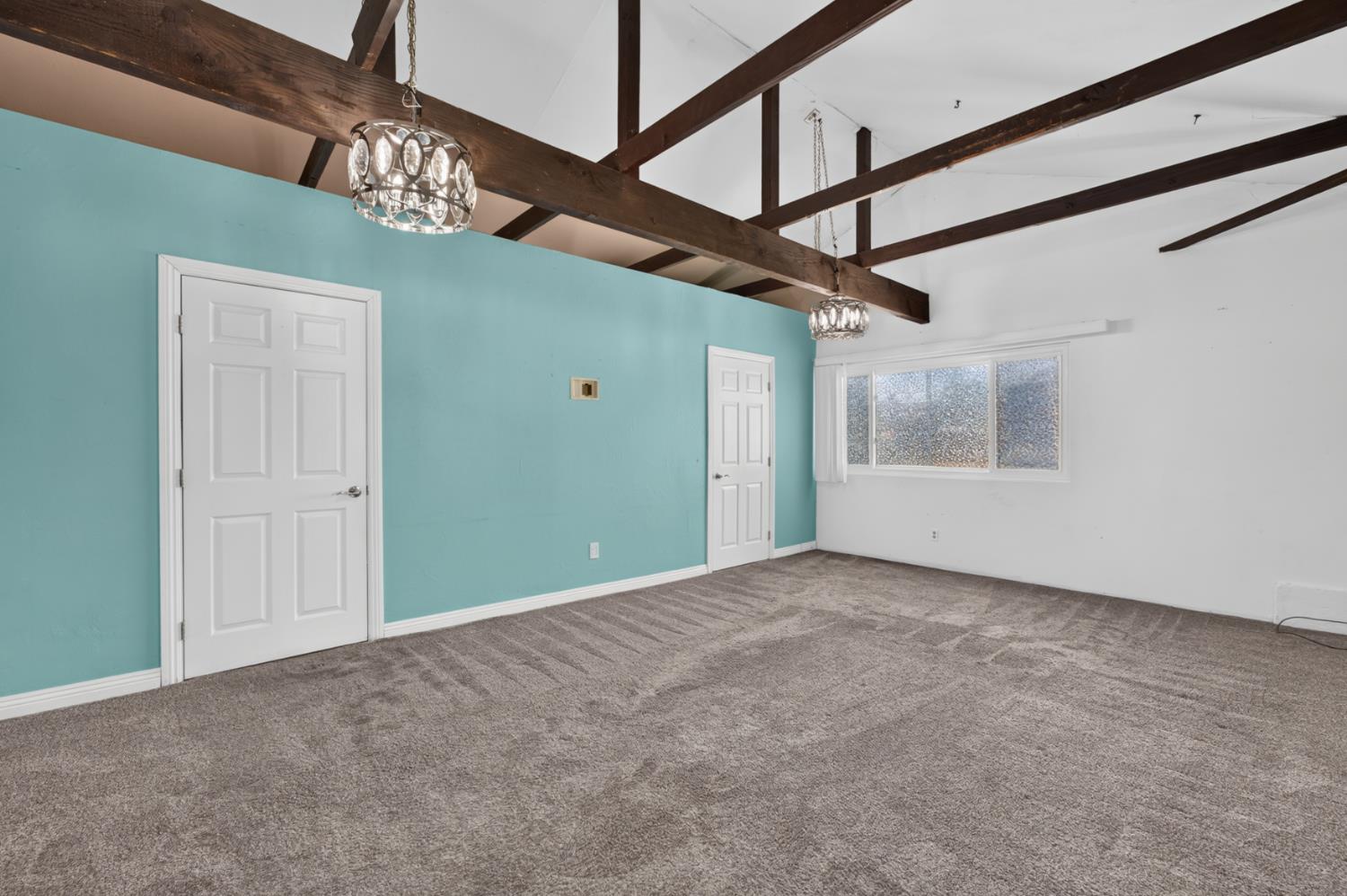 3708 Merrily Way Sacramento, CA 95821 - Photo 17 of 51 Vaulted ceiling with exposed wood beams, dual decorative pendant light fixtures, and a large window
