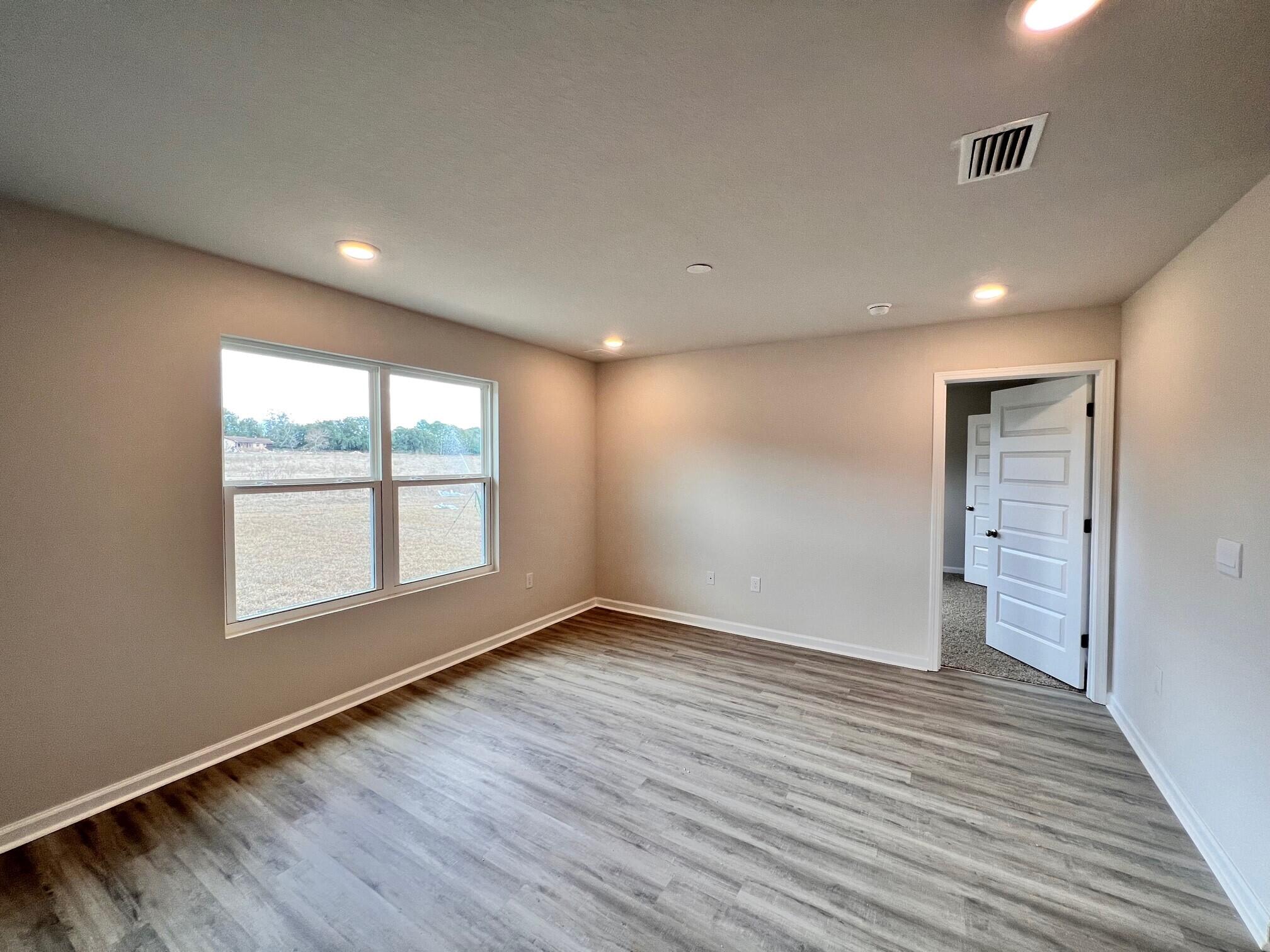 334 Flounder Street Crestview, FL 32539 - Photo 8 of 24 an empty room with wooden floor and windows