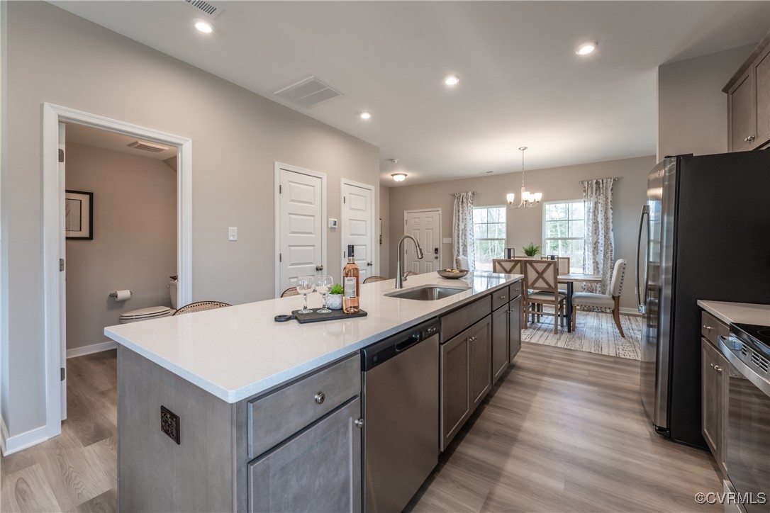 3413 Hopkins Road Richmond, VA 23234 - Photo 8 of 25 a large kitchen with kitchen island a sink a stove a refrigerator and a dining table with wooden floor