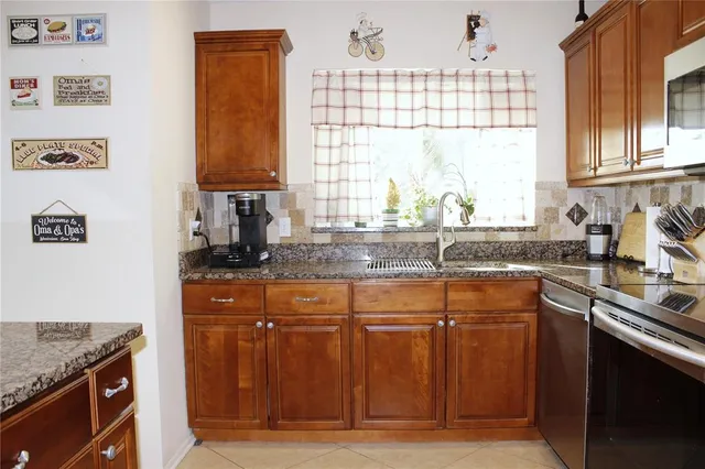 a kitchen with granite countertop a sink window and cabinets