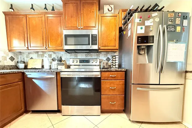 a kitchen with stainless steel appliances granite countertop a refrigerator a stove and a sink