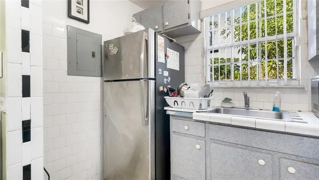 a kitchen with a sink a refrigerator a window and cabinets