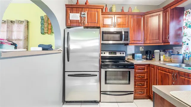 a kitchen with stainless steel appliances granite countertop a refrigerator a stove and a sink with large window