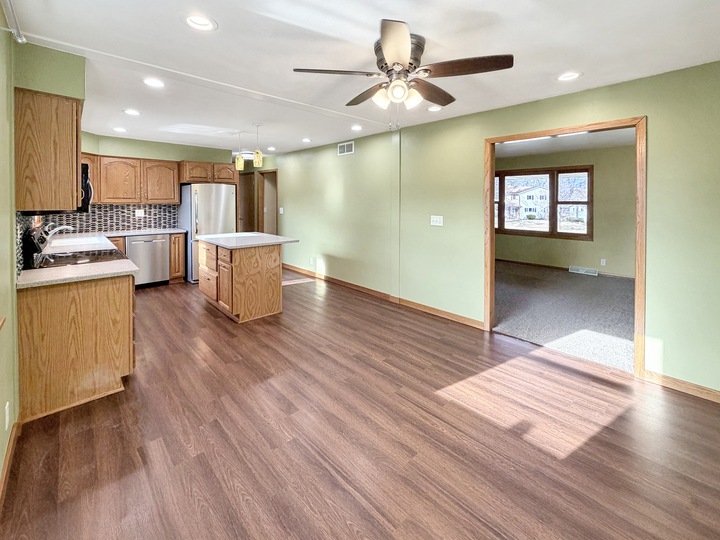 1419 Finch Street Freeport, IL 61032 - Photo 11 of 30 a view of a big room with wooden floor a ceiling fan and windows