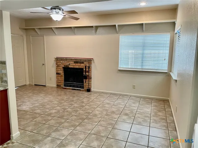 a view of an empty room with a fireplace and a window