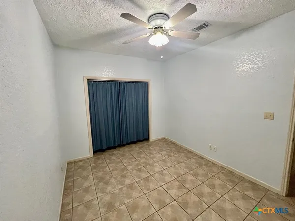 an empty room with windows and fan