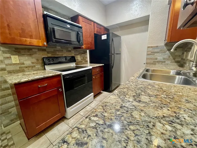 a kitchen with stainless steel appliances granite countertop a stove a sink and a microwave