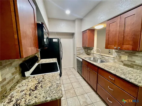 a kitchen with granite countertop a stove a sink and a microwave