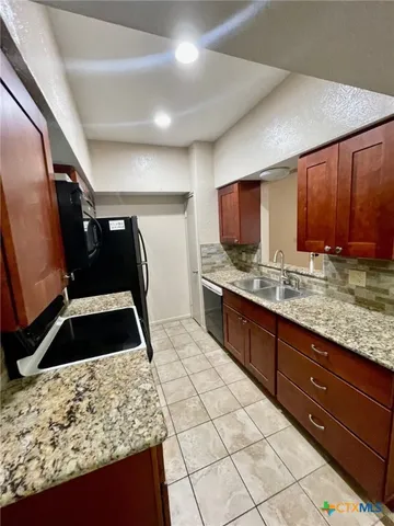 a kitchen with granite countertop a stove a sink and a microwave