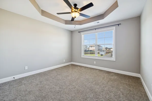 an empty room with windows and fan