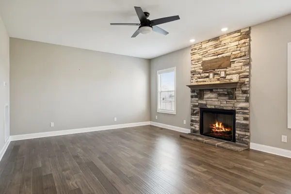 a view of an empty room with wooden floor fireplace and a window