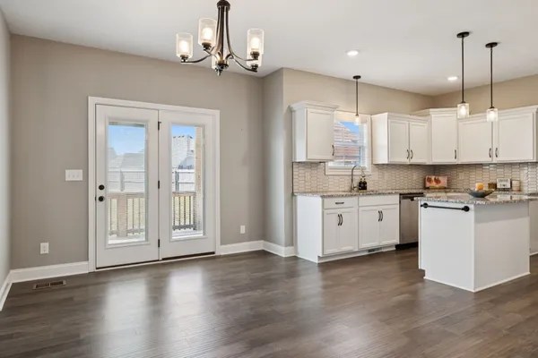a kitchen with stainless steel appliances granite countertop a refrigerator a sink dishwasher a stove and white cabinets with wooden floor