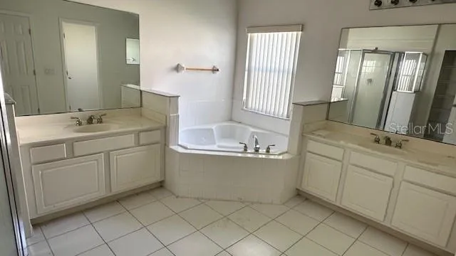 a bathroom with a double vanity sink mirror and bathtub