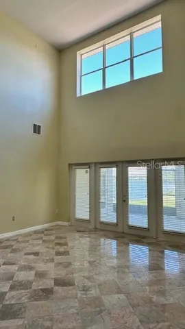 a view of an empty room with window and wooden floor
