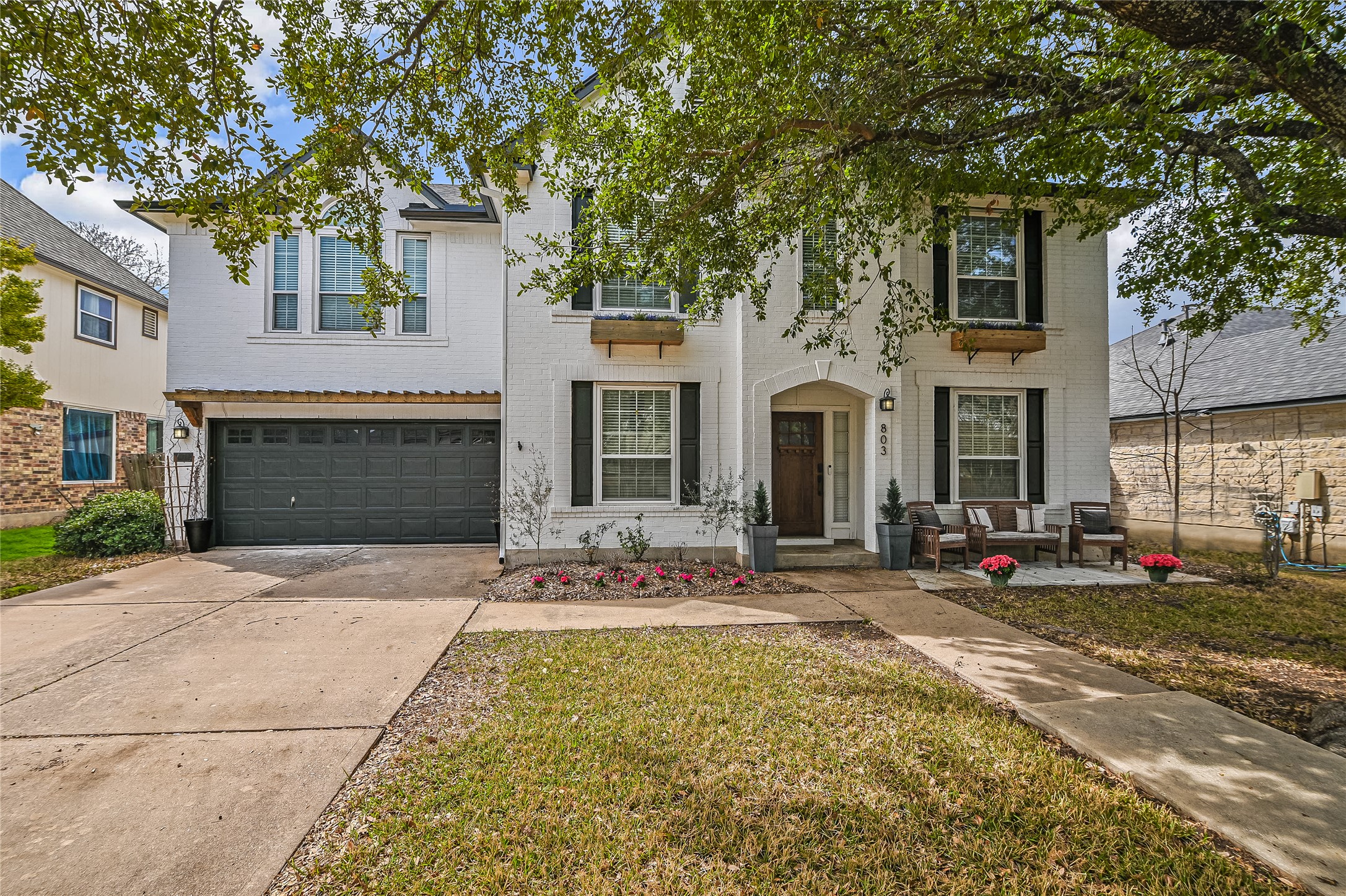 Traditional home featuring brick siding, driveway, an attached garage, and a front lawn