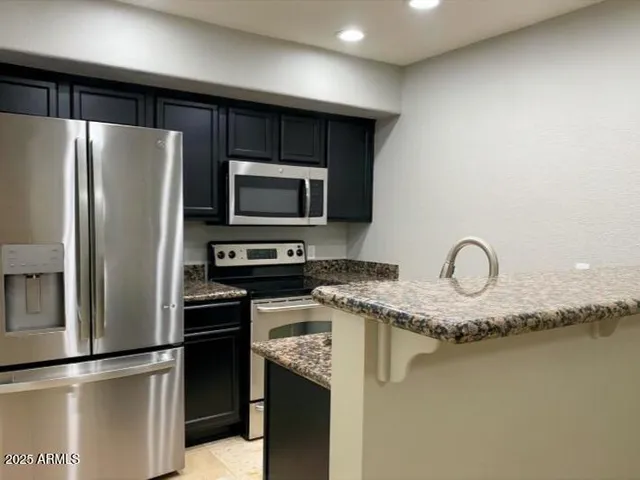 a kitchen with granite countertop stainless steel appliances and a refrigerator