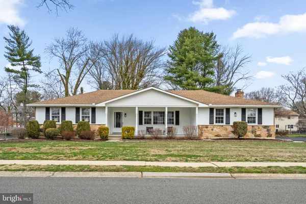 a front view of a house with a garden and trees