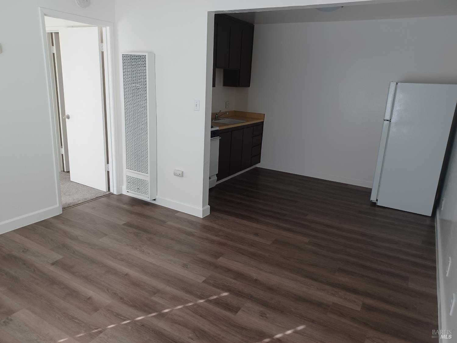 an empty room with wooden floor and cabinet