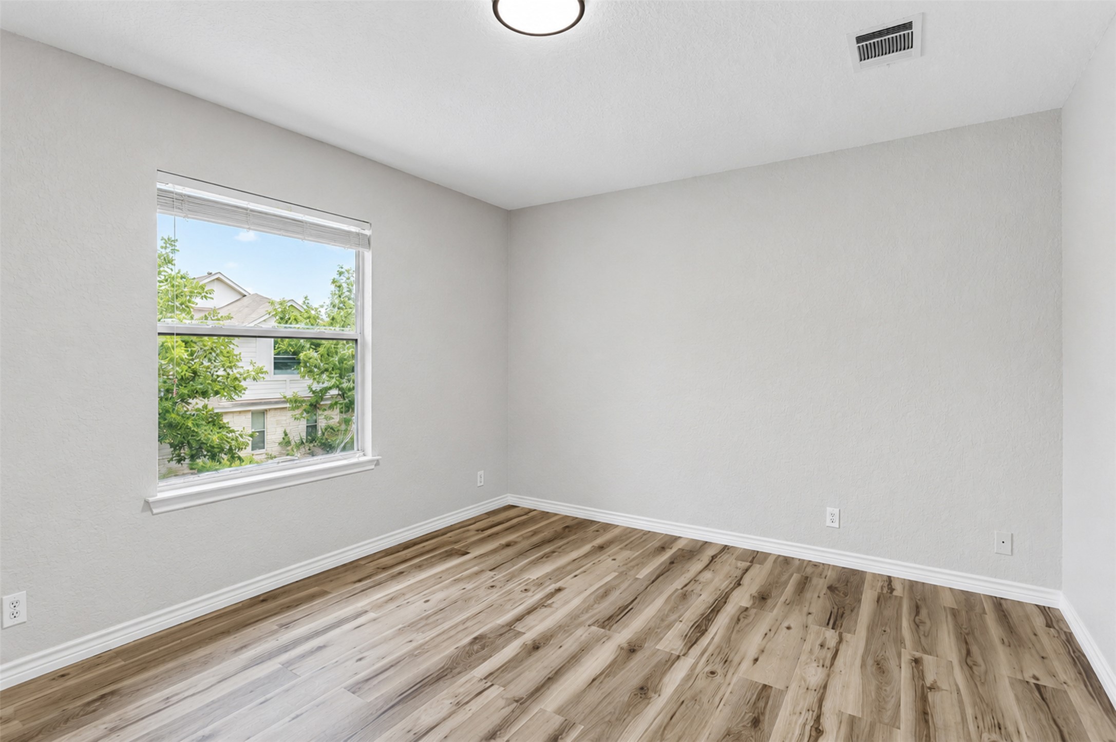 4523 Secure Lane Austin, TX 78725 - Photo 22 of 40 A quiet bedroom showcases light wood-look flooring and a generous window for natural illumination.