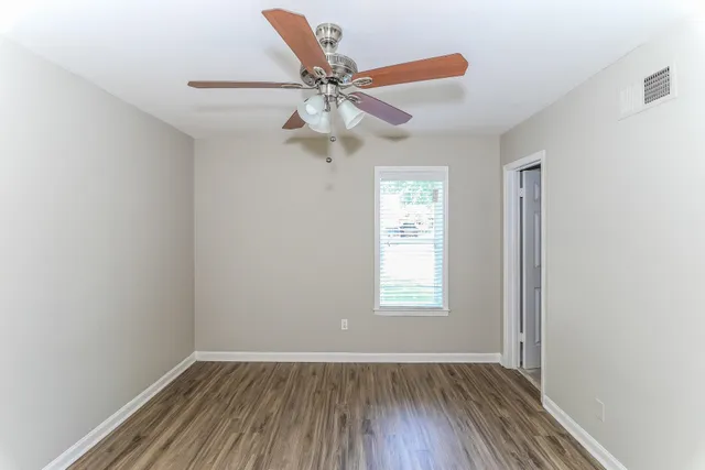 an empty room with windows and fan