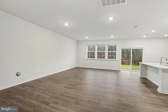 a view of empty room with wooden floor and windows