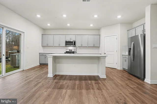 a kitchen with kitchen island a sink dishwasher a refrigerator and a stove with wooden floor