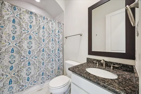 a bathroom with a granite countertop sink a toilet and a mirror