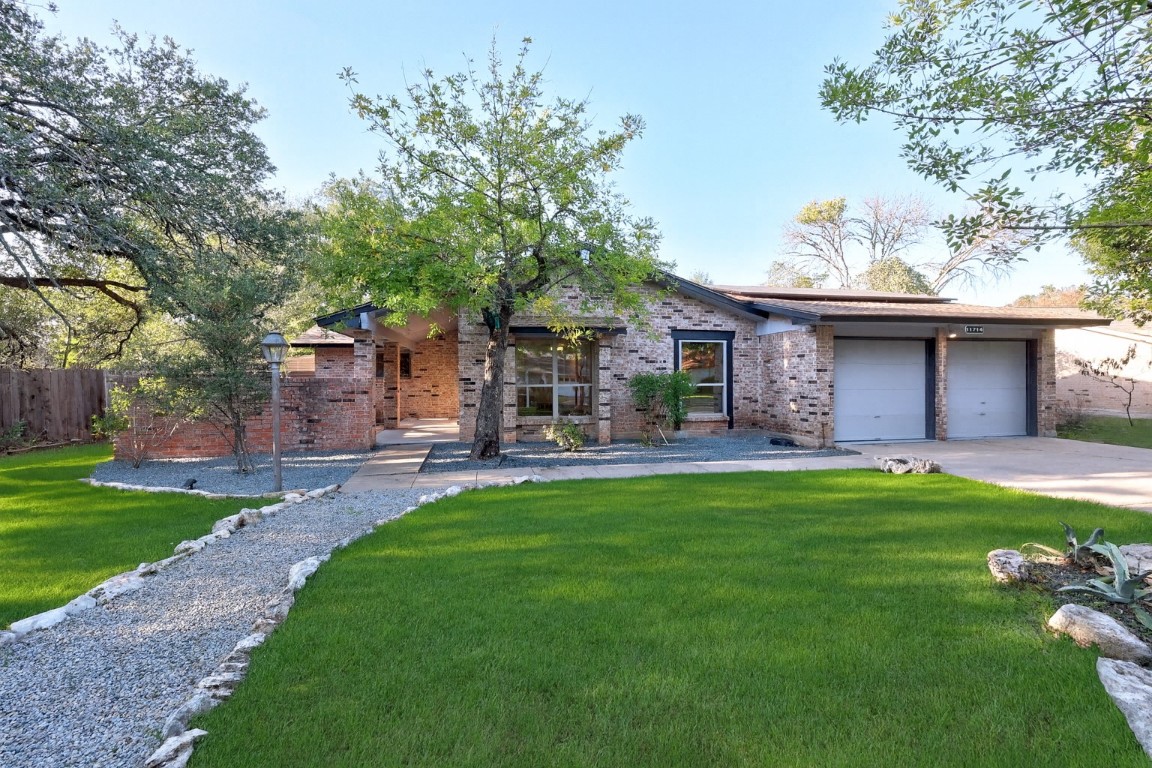 View of front facade with brick siding, driveway, and a garage