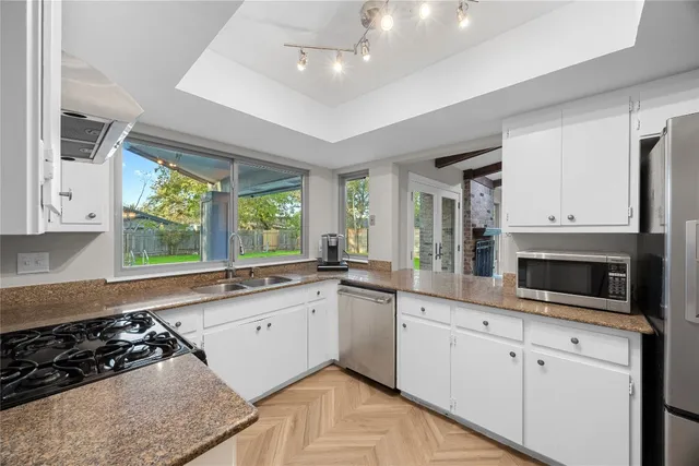 a large kitchen with stainless steel appliances granite countertop a stove a sink and a white cabinets