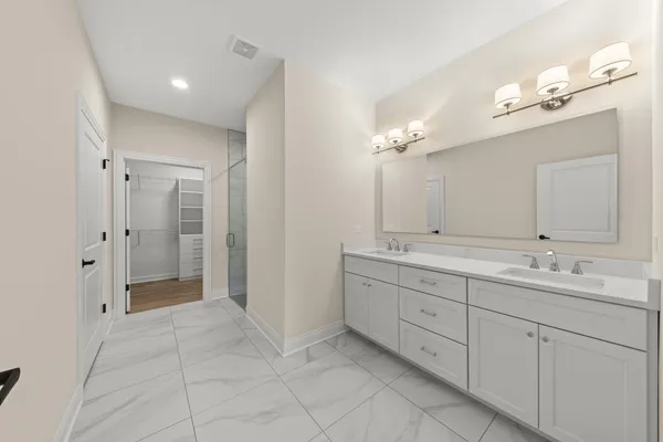 a spacious bathroom with a double vanity sink a mirror and a shower