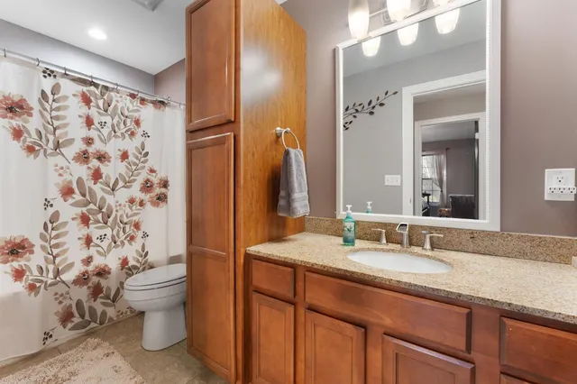 a bathroom with a granite countertop sink toilet and shower