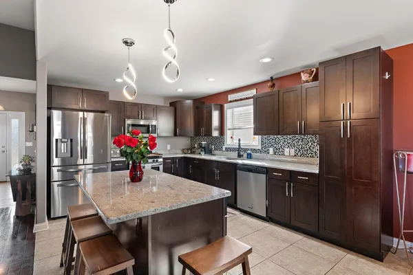 a kitchen with granite countertop kitchen island stainless steel appliances a sink and cabinets