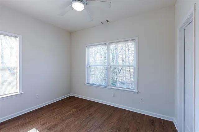 a view of an empty room with wooden floor and a window