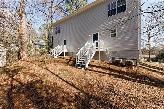 a view of a house with a yard chairs and wooden fence